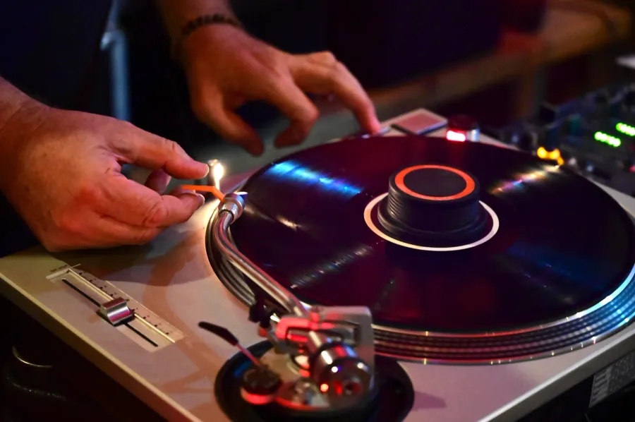 Hände an einem beleuchteten DJ-Pult während der Sommerparty